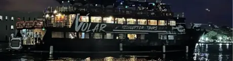 Fiesta nocturna en barco por la bahía, con música, bebidas y la ciudad iluminada.