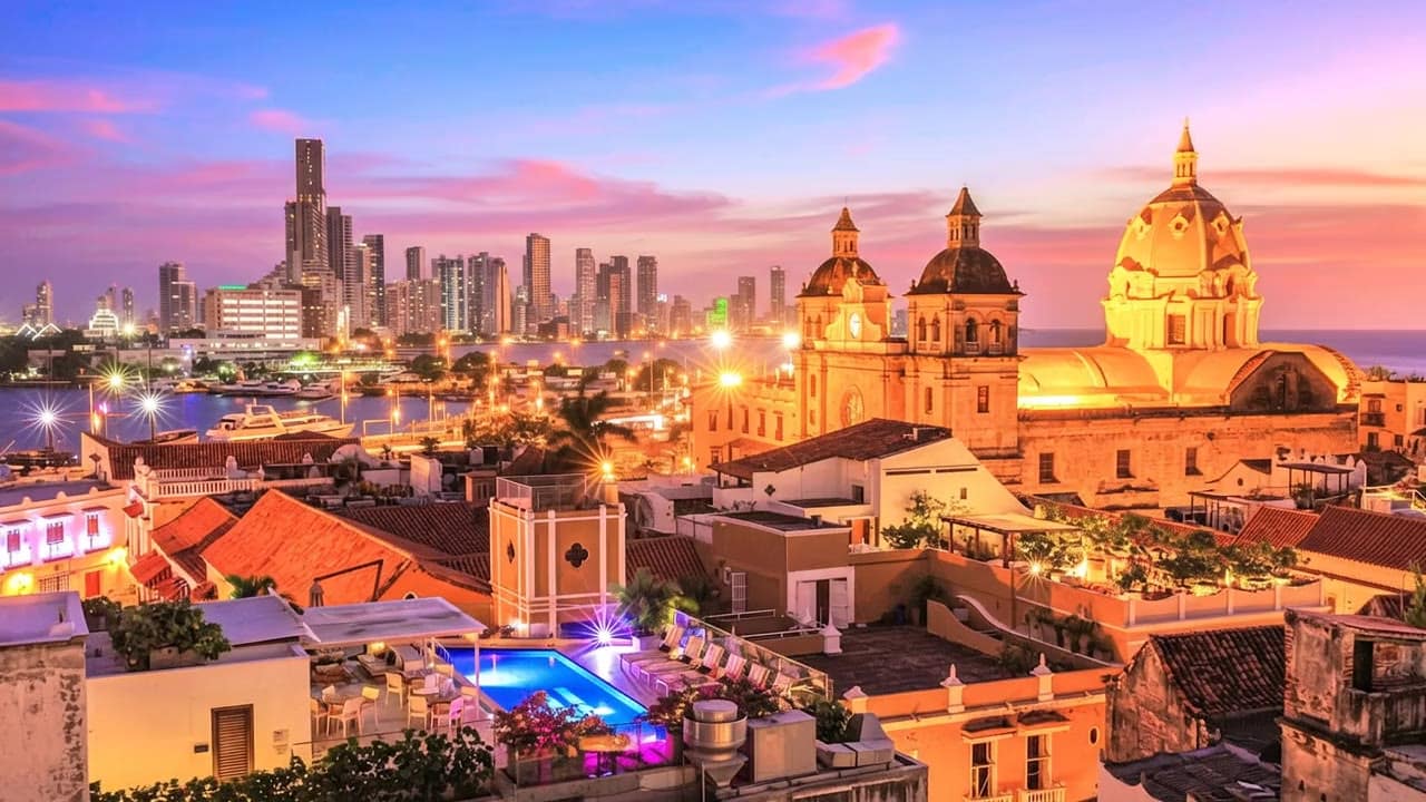 Vista aérea del Centro Histórico de Cartagena al atardecer, con la cúpula de San Pedro Claver y el skyline de Bocagrande al fondo